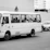 A modern bus with happy passengers boarding for a factory worker transport trip.
