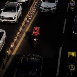 A busy city street with delivery vehicles and a courier on a motorcycle.