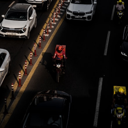 A busy city street with delivery vehicles and a courier on a motorcycle.
