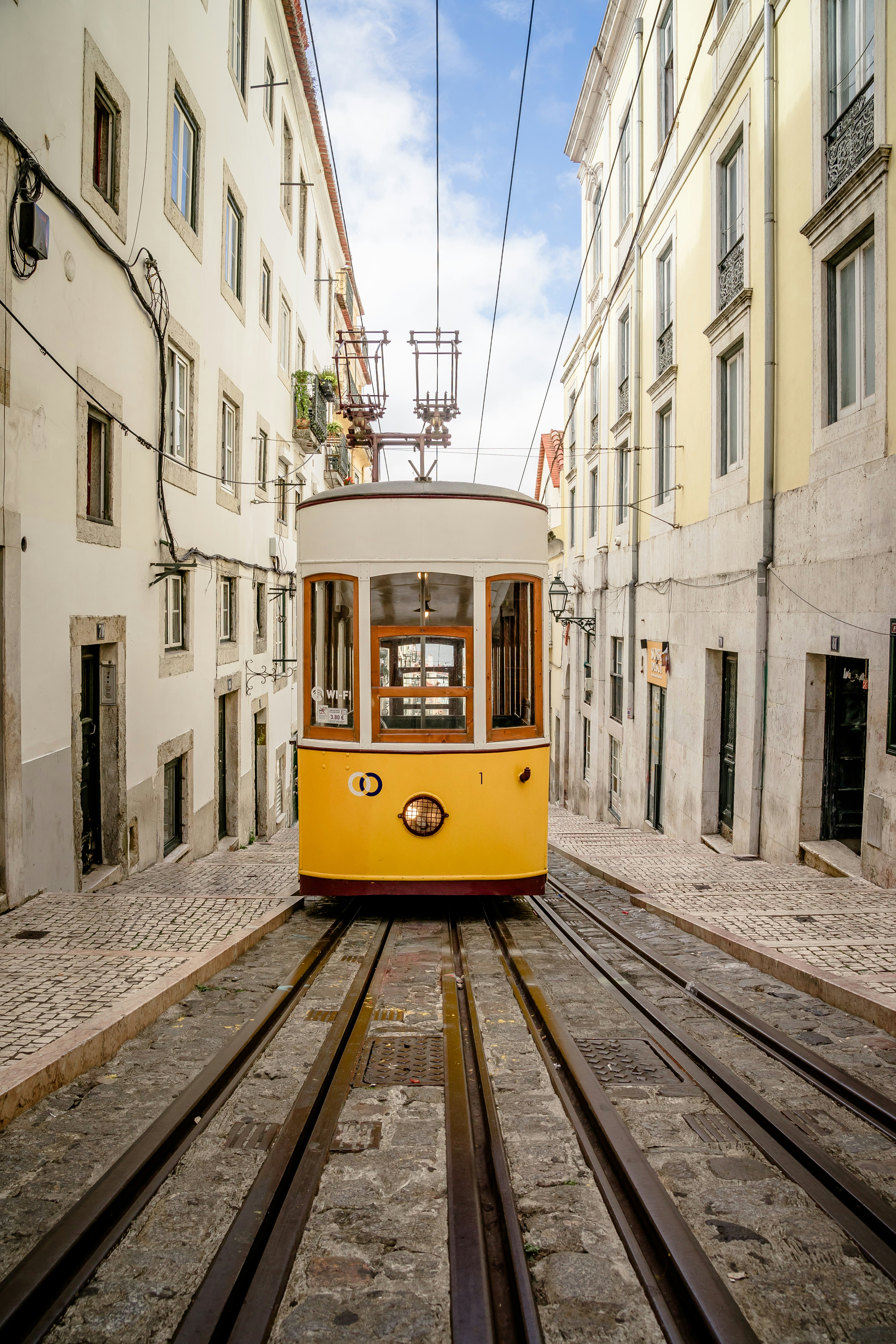 a yellow trolley car traveling down a street next to tall buildings