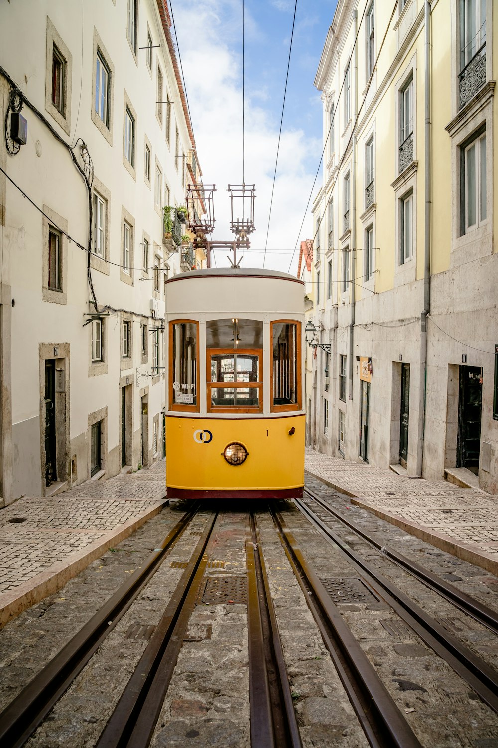 a yellow trolley car traveling down a street next to tall buildings