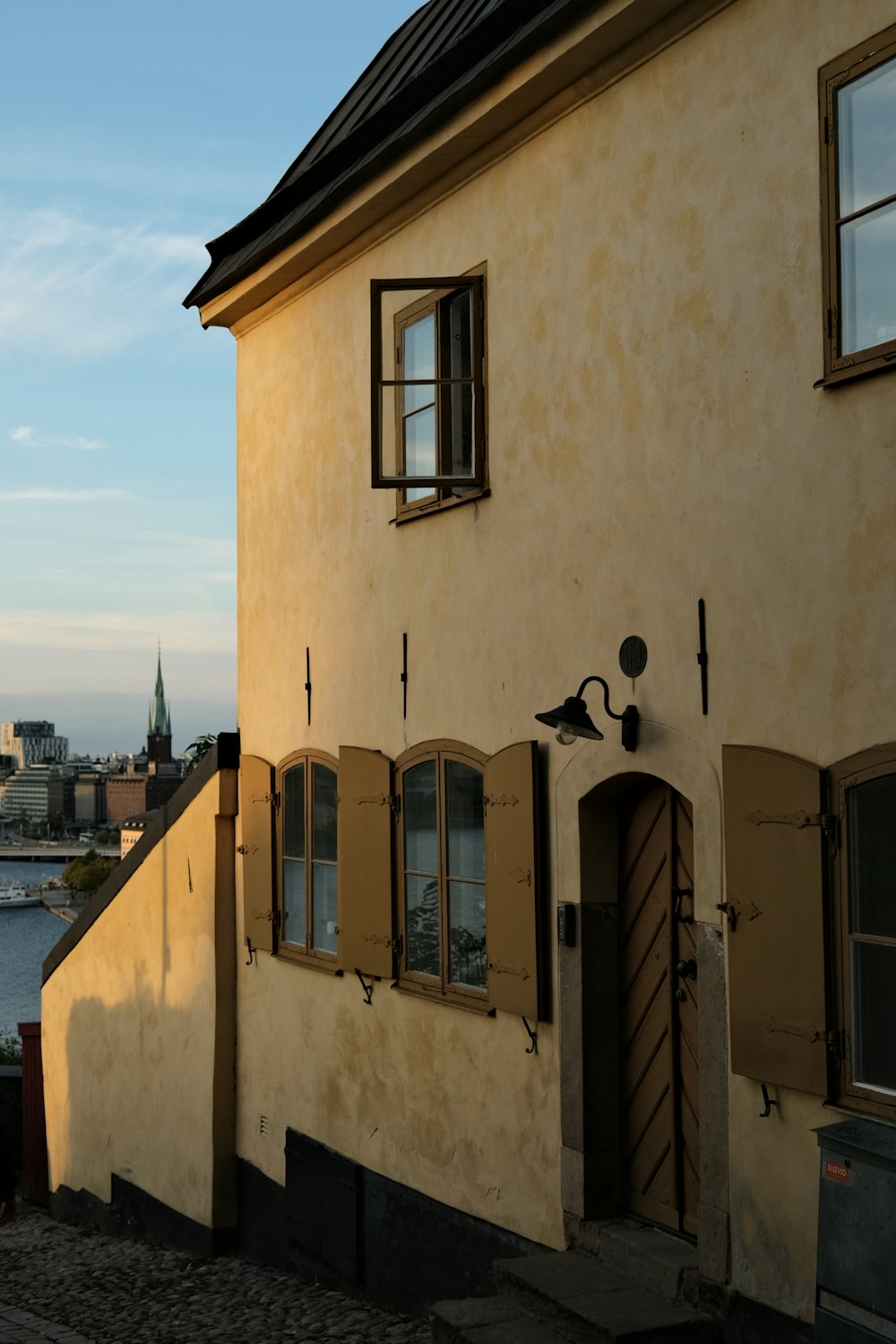 a building with windows and shutters next to a body of water