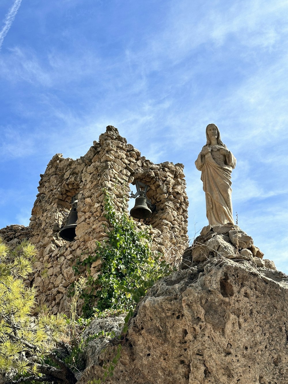 Una estatua en la cima de una roca junto a un edificio