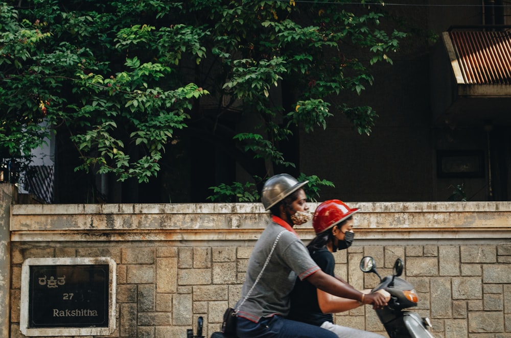 a man and a woman riding on the back of a moped