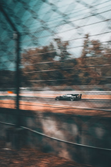 A close-up shot of a speeding race car blurred against a sleek race track.