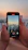 A smiling woman recording a video with her smartphone outdoors during golden hour.