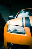 Close-up of a matte black Challenger hood with bold orange racing stripes under bright sunlight.