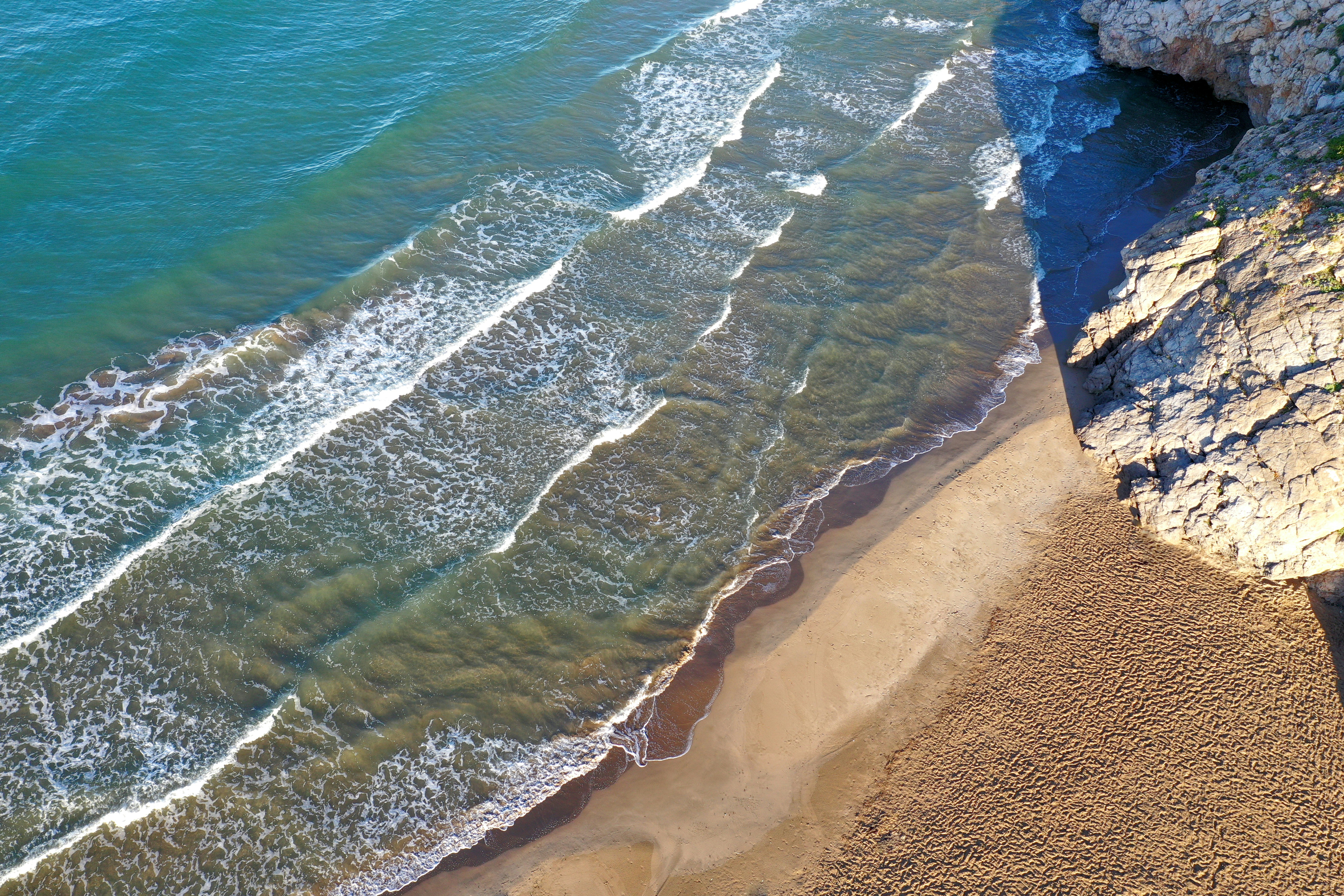 an aerial view of a beach with waves coming in