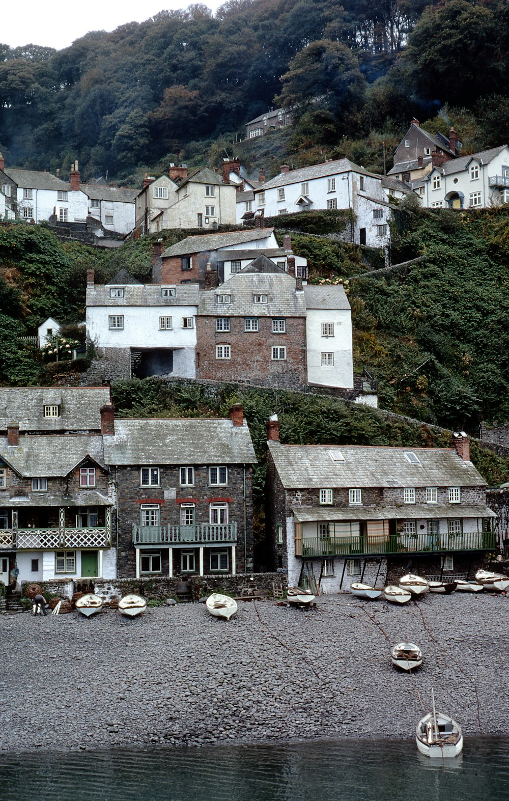 a group of houses sitting on top of a hill next to a body of water