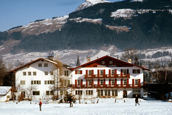 A large white building with red shutters in front of a mountain — Kitzbühel, Austria