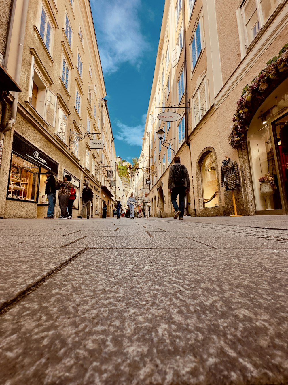 a group of people walking down a street next to tall buildings