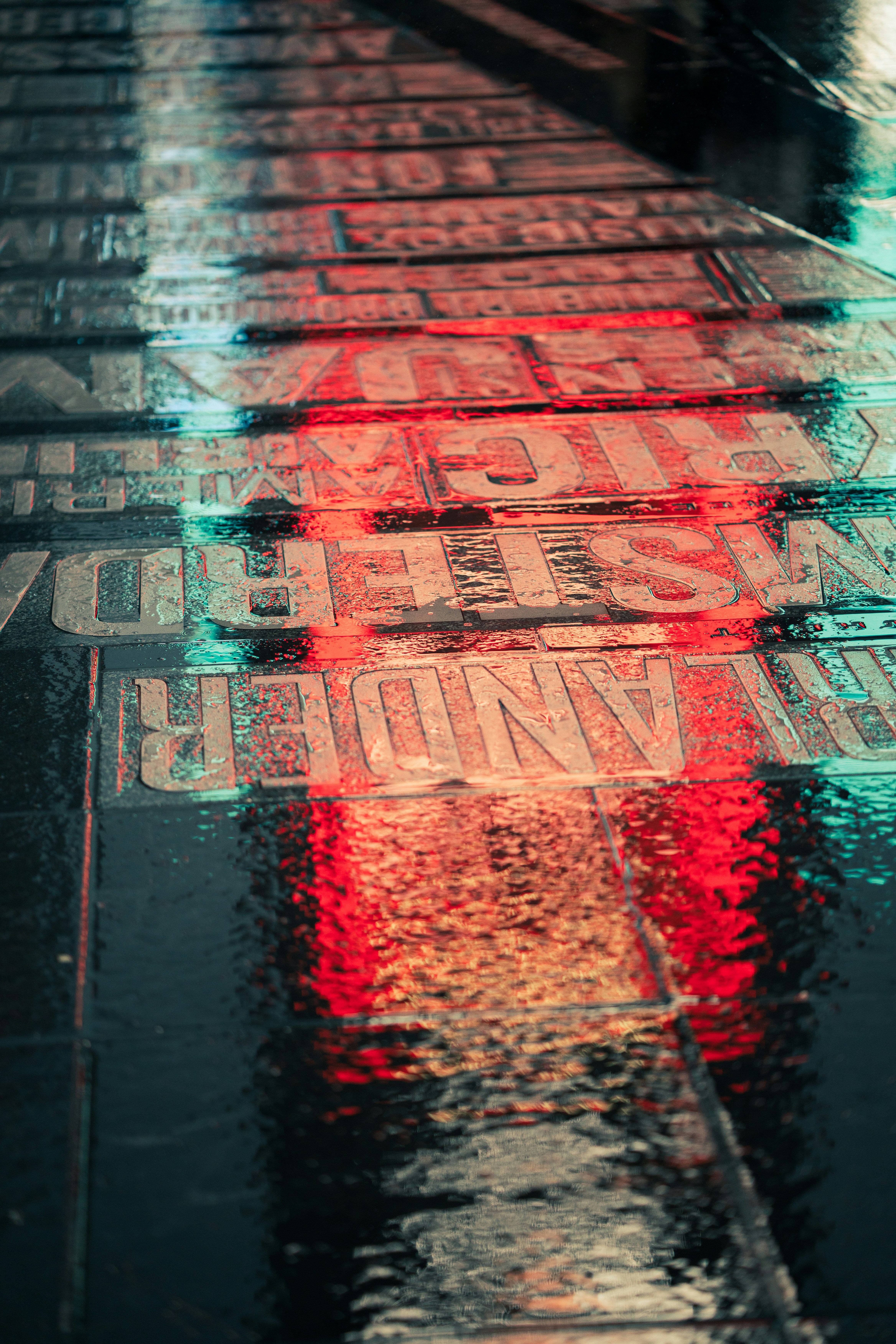 a wet sidewalk with a red stop sign on it