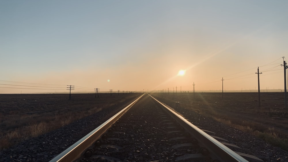 a train track with the sun setting in the distance