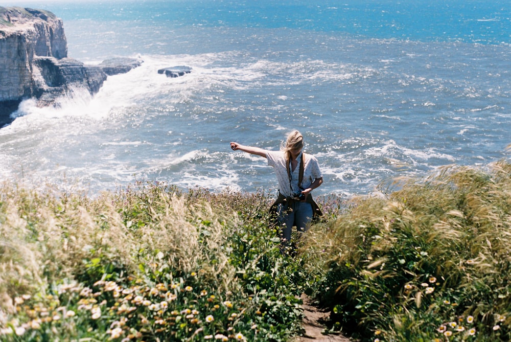 a woman standing on top of a cliff near the ocean