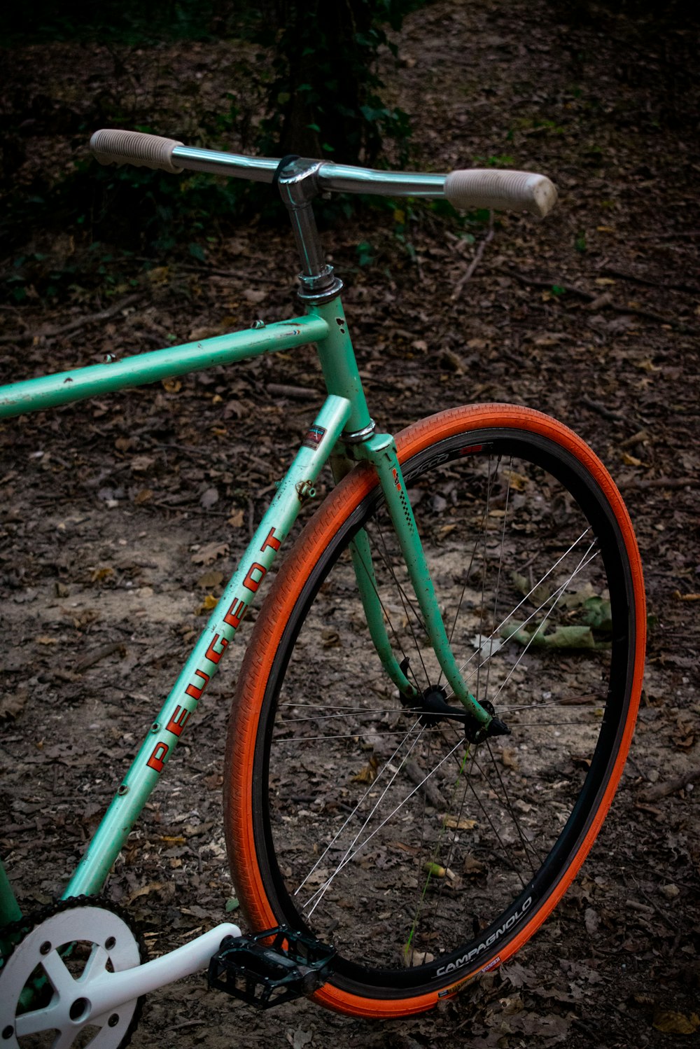 a green and orange bike parked on a dirt road