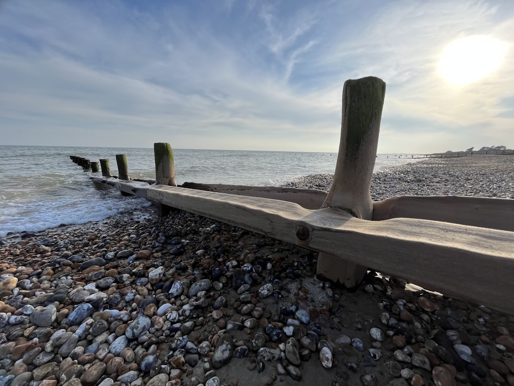 a wooden bench sitting on top of a rocky beach