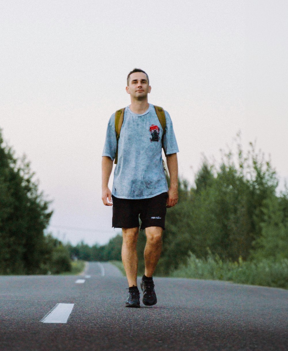 a man walking down a road with a backpack on