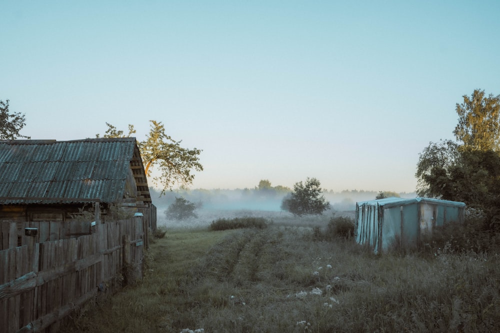 a foggy field with a shack in the distance