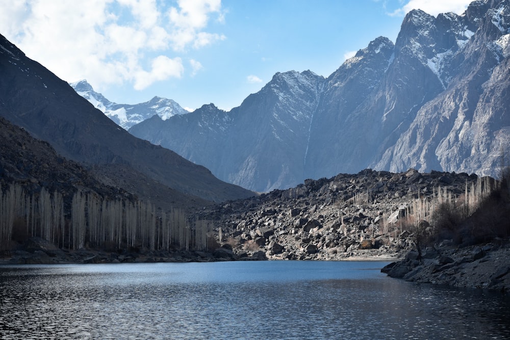 a body of water surrounded by mountains under a blue sky