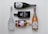 Five bottles of various alcoholic beverages are arranged neatly on a light background. The bottles include a white frosted glass vodka bottle, a black rectangular gin bottle, a brown glass whiskey bottle, and two bottles of sparkling wine with decorative labels.