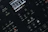 Close-up of a digital synthesizer control panel with various buttons and a small display screen showing audio parameters. The layout features buttons for saving, editing, and managing sound settings with labels like 'Analog Four MKII', 'Tap Tempo', and 'Edit Song'.