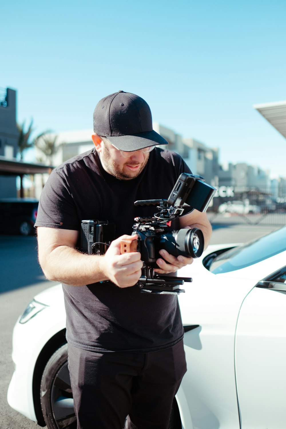 a man standing next to a white car holding a camera