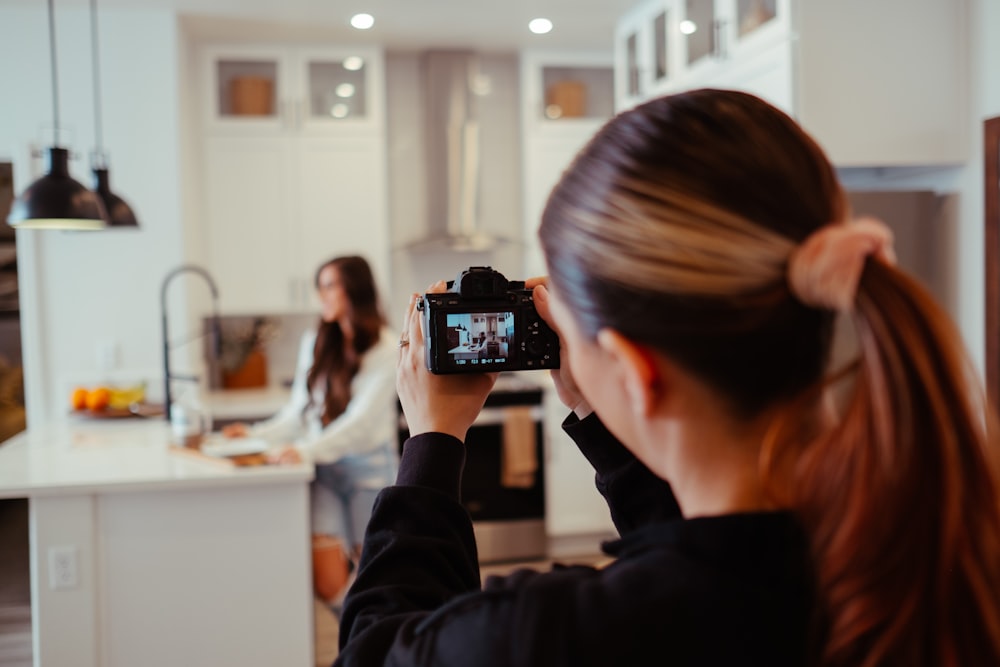 a woman taking a picture of herself in a kitchen