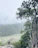 A smiling hiker standing on a rocky overlook with lush green Croatian national park scenery stretching behind.