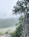 A smiling hiker standing on a rocky overlook with lush green Croatian national park scenery stretching behind.