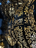 Ornate lamps with intricate cut-out patterns allow light to shine through, creating an elegant, geometric and floral design. The dark metal contrasts with the golden glow of the lights, enhancing the decorative patterns.