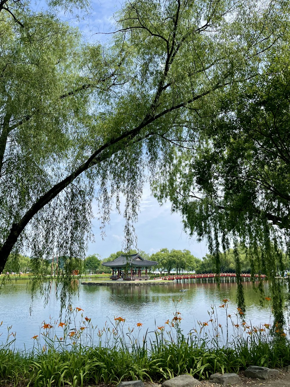 a lake surrounded by trees with a pavilion in the background