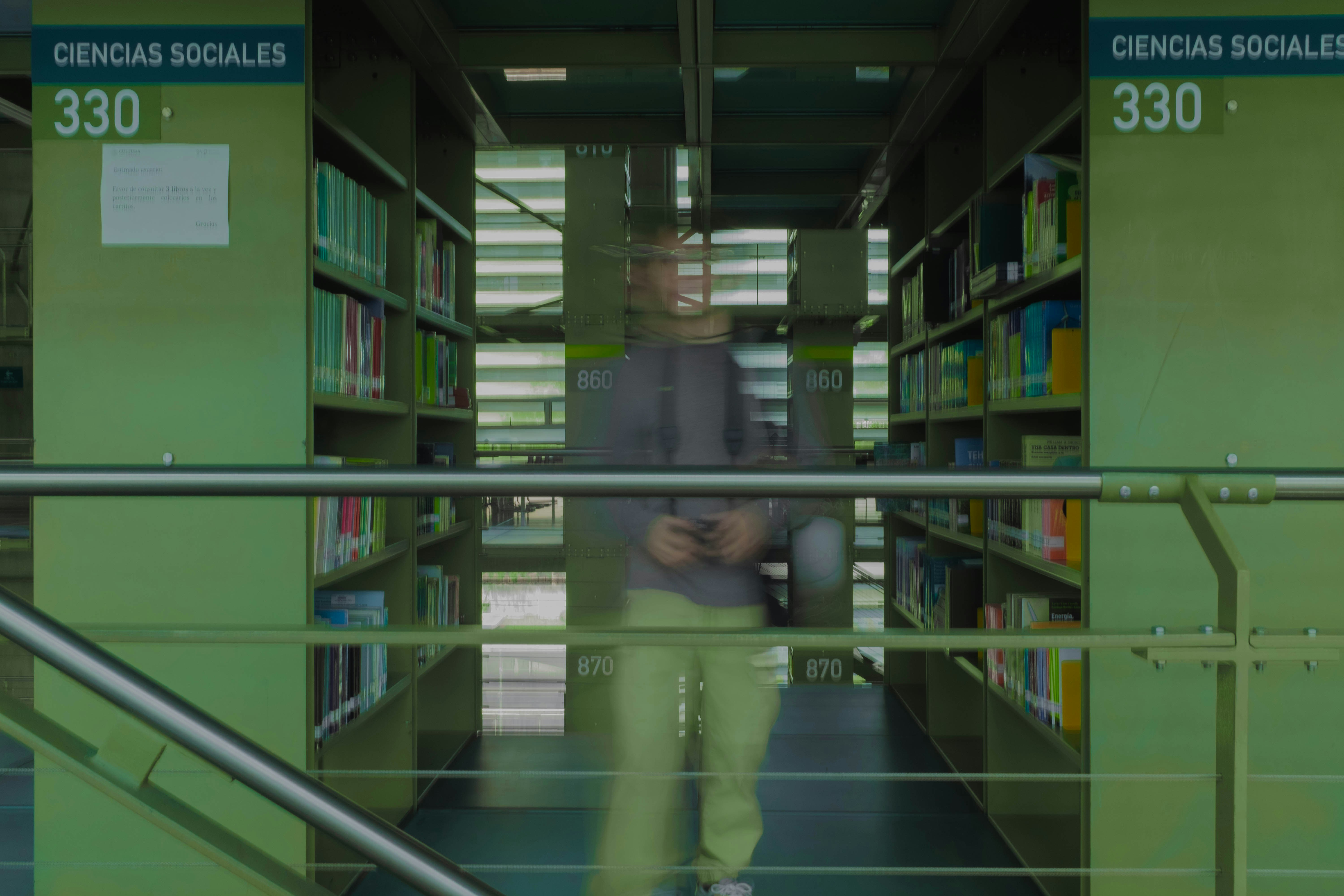 a man walking down a set of stairs in a library