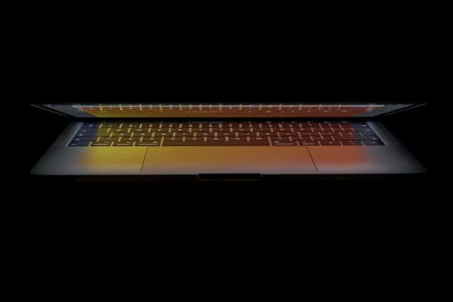 A sleek laptop open on a wooden desk with soft natural light highlighting its keyboard.