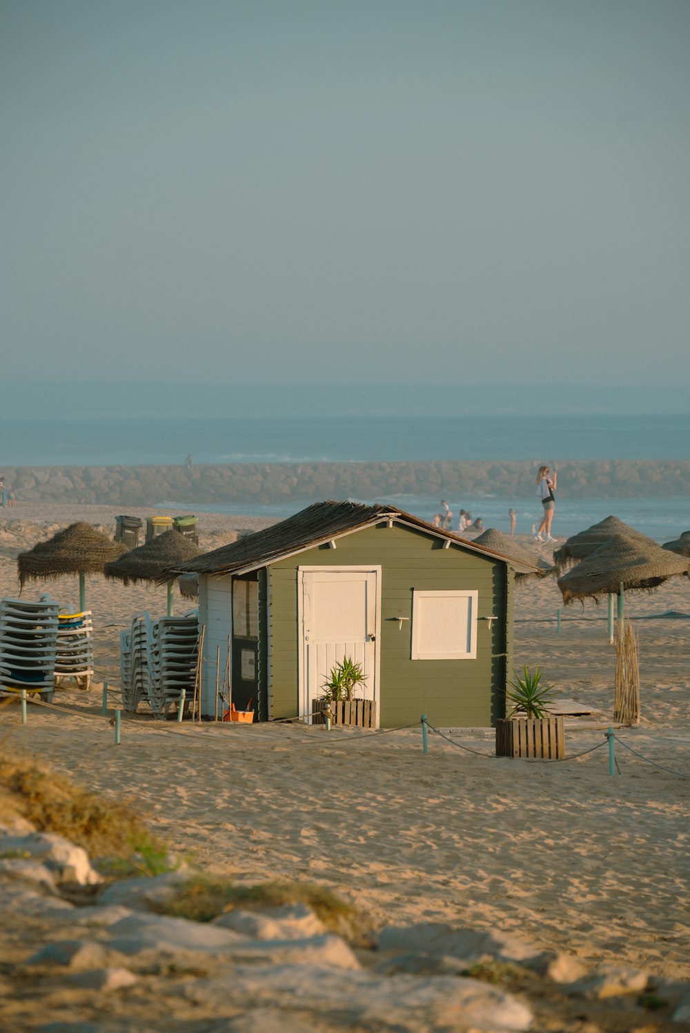 a small green building on a sandy beach