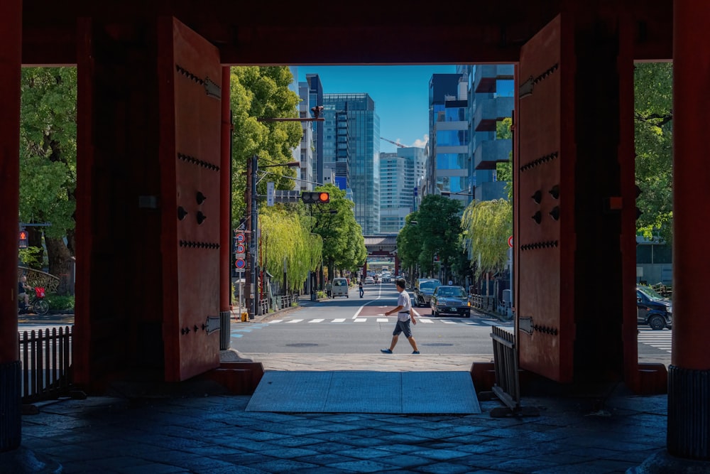 a man walking through an open doorway in a city