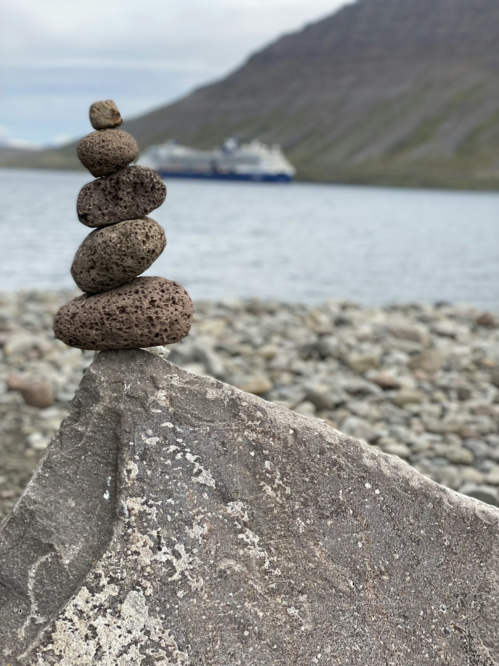 a stack of rocks sitting on top of a rock next to a body of water