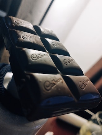 High-definition close-up image of rich, textured dark chocolate blocks with a matte finish, accented by subtle golden highlights.