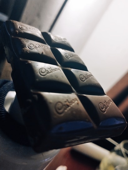 Close-up of a rich, glossy chocolate bar with a sprinkle of sea salt on top, highlighting its smooth texture.