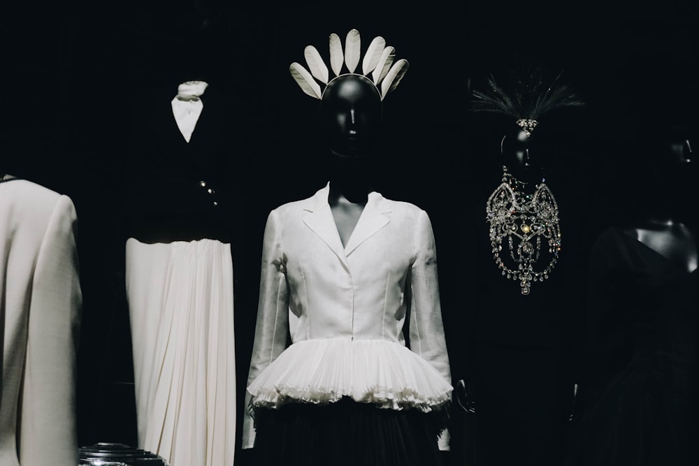 a black and white photo of mannequins and dresses