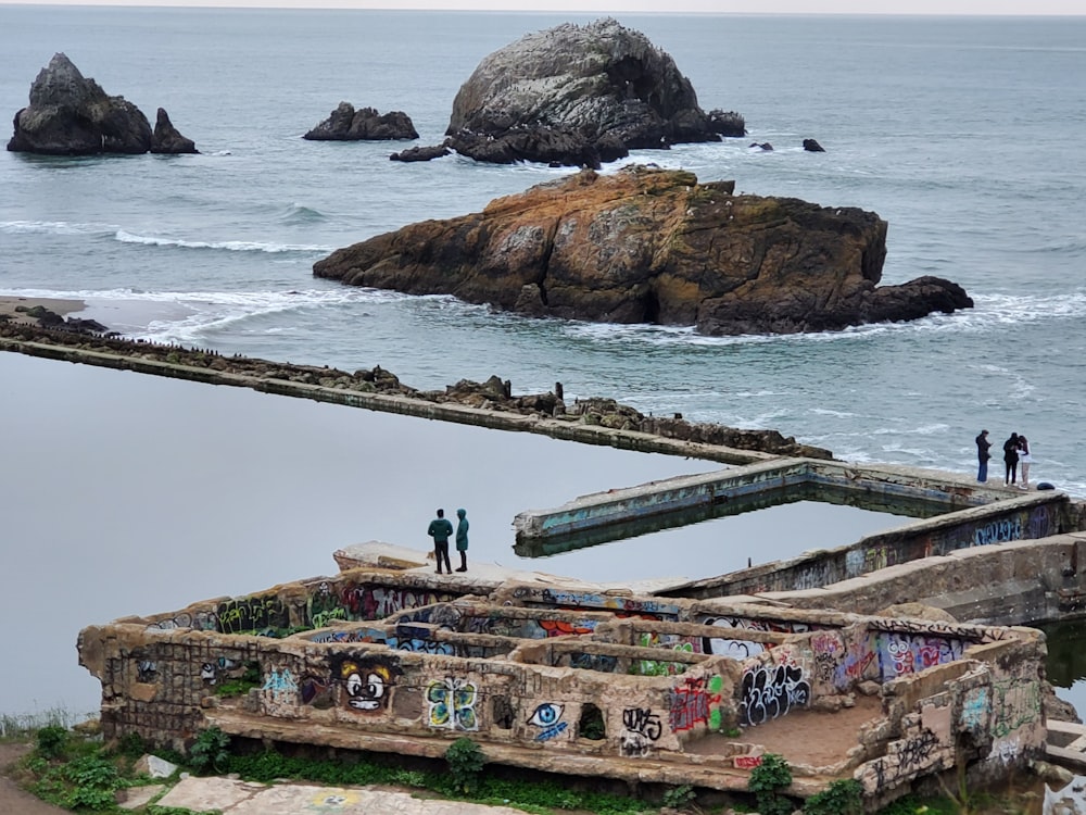 a group of people standing on top of a pier next to the ocean