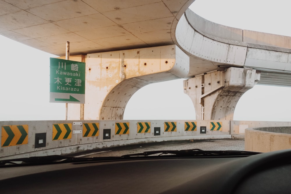 a car driving under a bridge with a sign on it