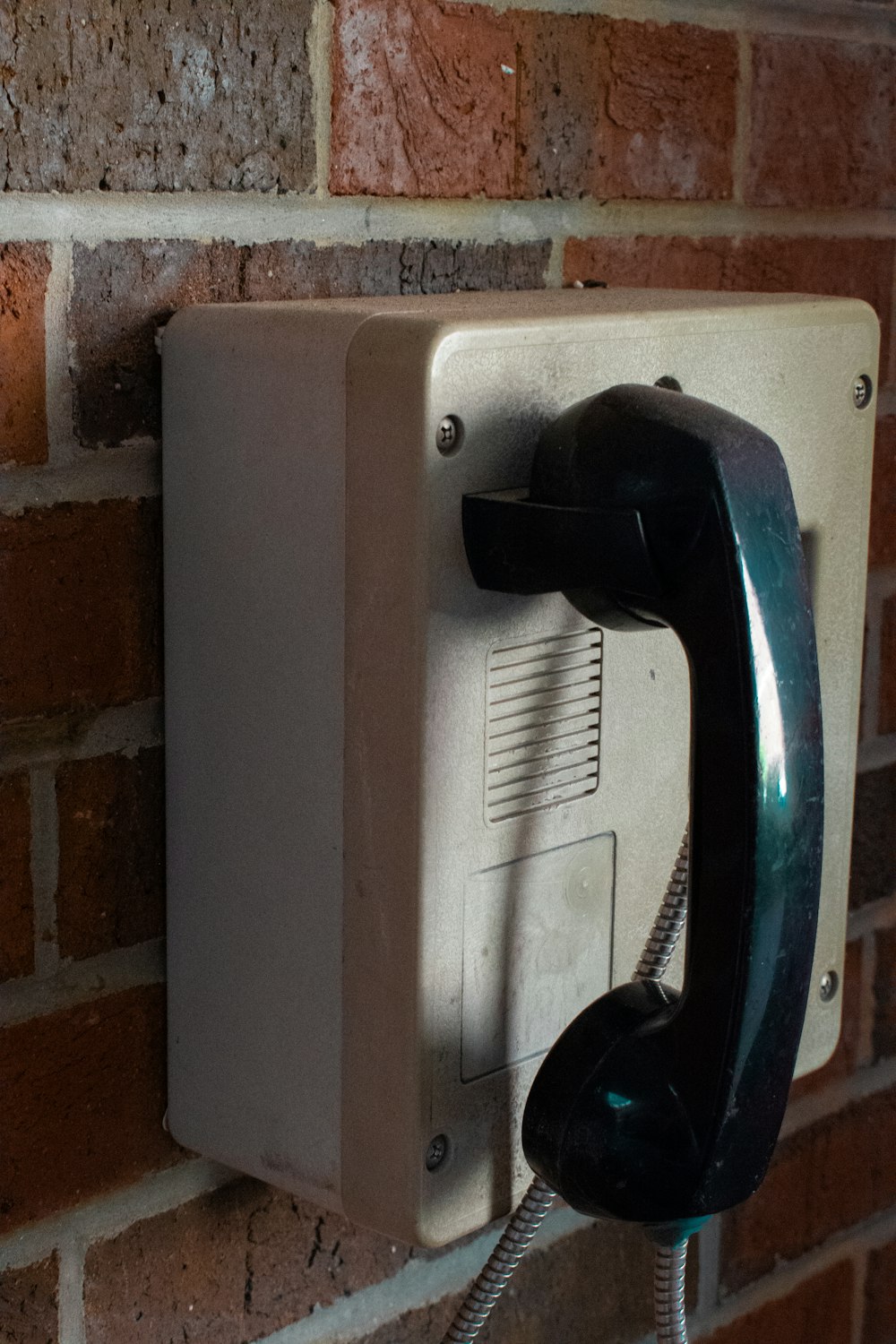 an old phone is attached to a brick wall