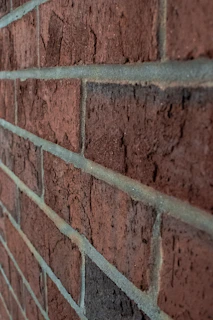 Close-up of a red brick wall before and after cleaning, highlighting veewave's attention to detail and color contrast.
