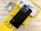 A smartphone with a black back featuring dual camera lenses is placed atop a partially open yellow box. The box is labeled 'C53' and contains various accessories, such as a charger and cables. A protective phone case is also visible beside the box.