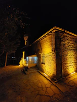 Evening shot of alameen nexus facility exterior, the terracotta walls glowing warmly under industrial lighting.