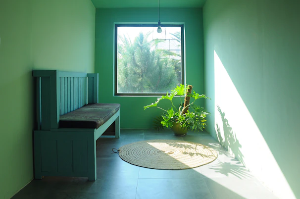 Spacious guest room featuring minimalist design with beige and deep green accents, large windows letting in natural light.