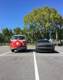 A modern cargo van and sprinter van parked side by side with a city skyline in the background under a clear sky.