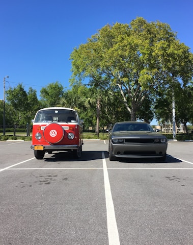 A modern cargo van and sprinter van parked side by side with a city skyline in the background under a clear sky.
