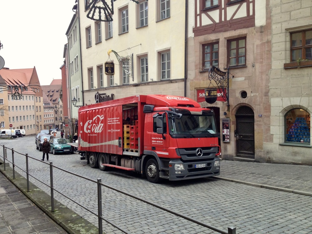 a red truck driving down a street next to tall buildings