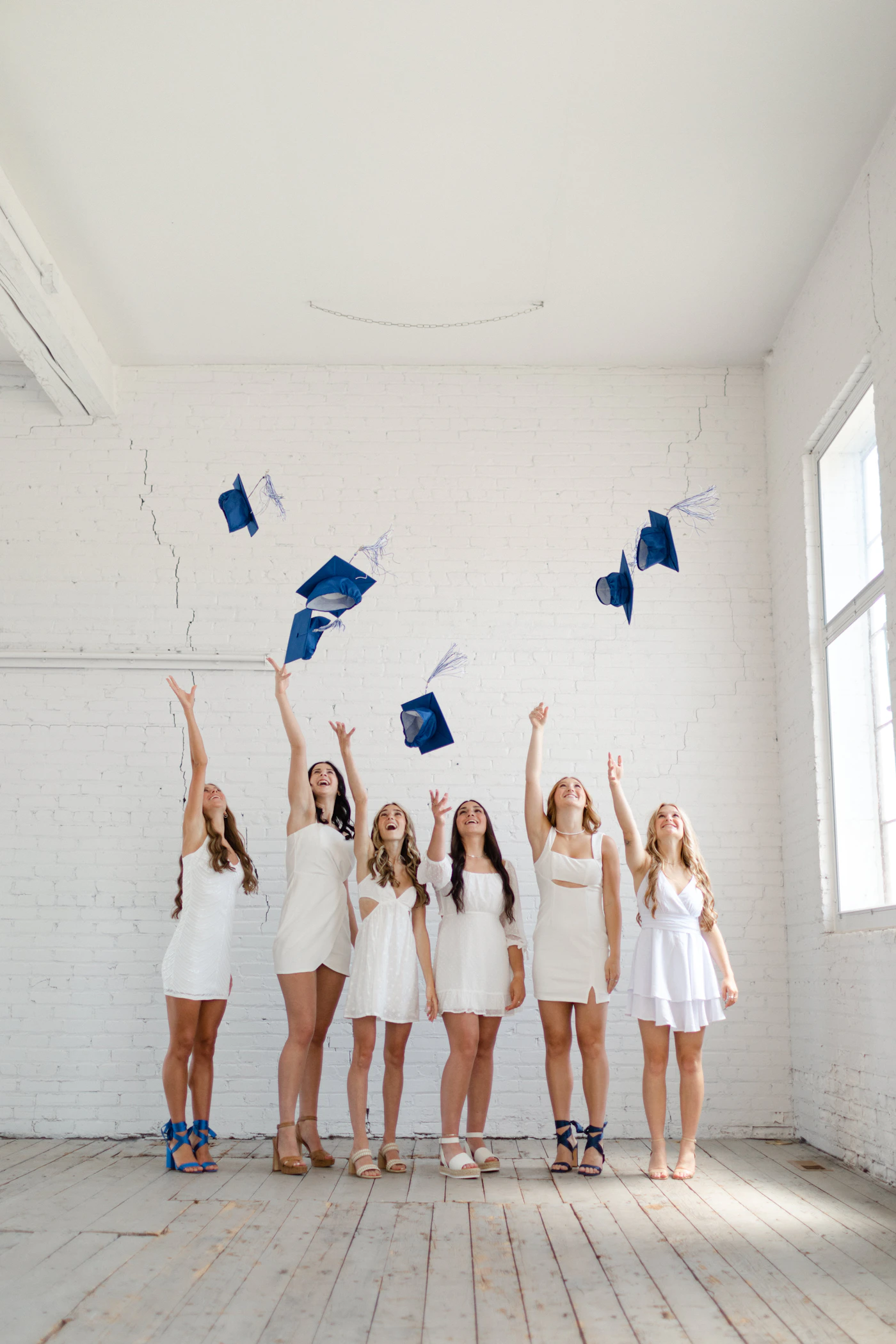 School leavers in graduation gowns throwing caps into a bright sky